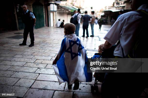 An Israeli boy is covered with his national flag as Israelis take part in a march marking Jerusalem Day on May 12, 2010. In Jerusalem's old city....