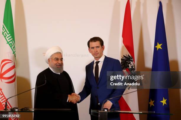 Iranian President Hassan Rouhani shakes hands with Austrian Prime Minister Sebastian Kurz as they hold a joint press conference in Vienna, Austria on...