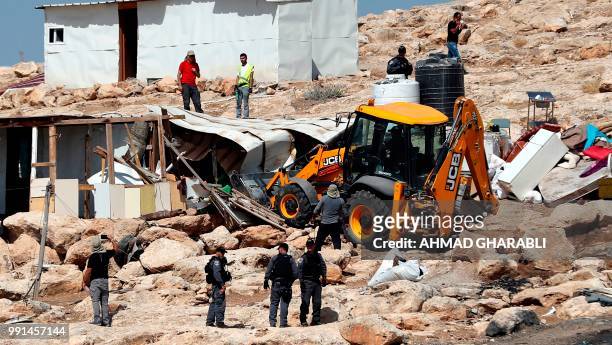 Israeli police secure a bulldozer demolishing structures at the Bedouin village of Abu Nuwar, near Abu Dis, east of Jerusalem in the occupied West...