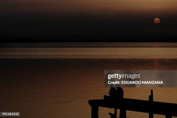 a couple watching the sunset in the lagoon of vale - manzana stock pictures, royalty-free photos & images