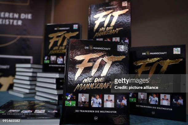 The book "Fit like the National Squad" by the German national soccer team's fitness trainers, Kugel and Dietrich, standing on a table during its...