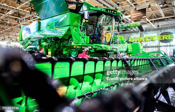 Visitors watching a combine harvester at the stand of the John Deere company in the agricultural technology fair Agritechnica in the Hanover...