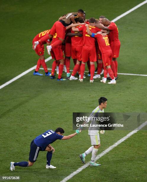 Eiji Kawashima of Japan helps his team mate Gen Shoji to his feet as Nacer Chadli of Belgium is congratulated on scoring the winning goal during the...