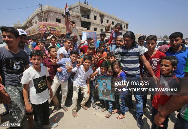 Syrian civilians pose for a photograph as Syrian government forces recently recaptured the village of Ghariyah ash Sharqiyah from the rebels, in the...