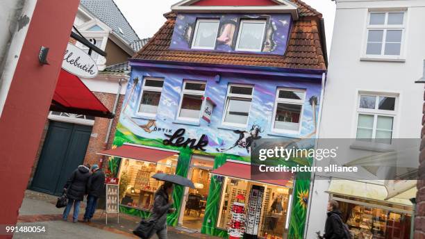 Passersby walk passed a building with a huge graffiti in the pedestrian zone in Aurich, Germany, 14 November 2017 . Photo: Mohssen Assanimoghaddam/dpa