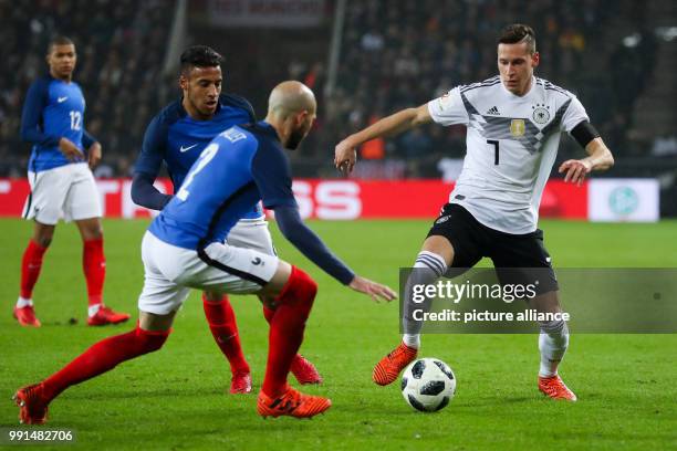 Germany's Julian DRaxler vying for the ball against France's Corentin Tolisso and Christophe Jallet during the international soccer match between...