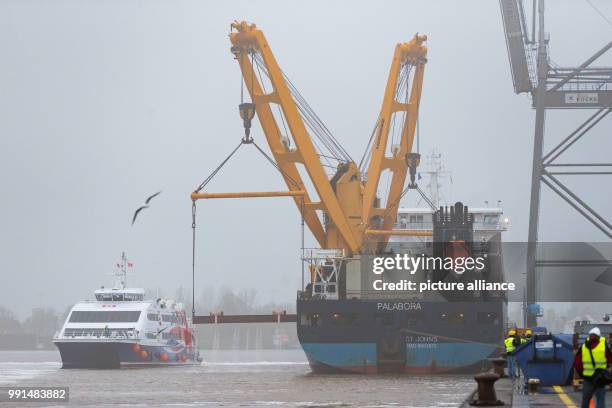 The catamaran "Halunder Jet" sailing along the side of the heavy cargo freighter "Palabora" in the harbour of Emden, Germany, 15 November 2017. The...