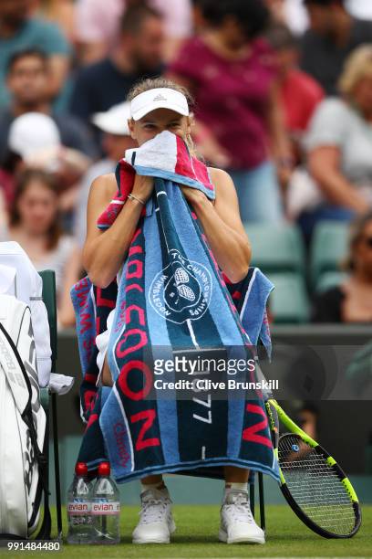 Caroline Wozniacki of Denmark uses her towel to protect herself from the flying ants during a break in her Ladies' Singles second round match against...