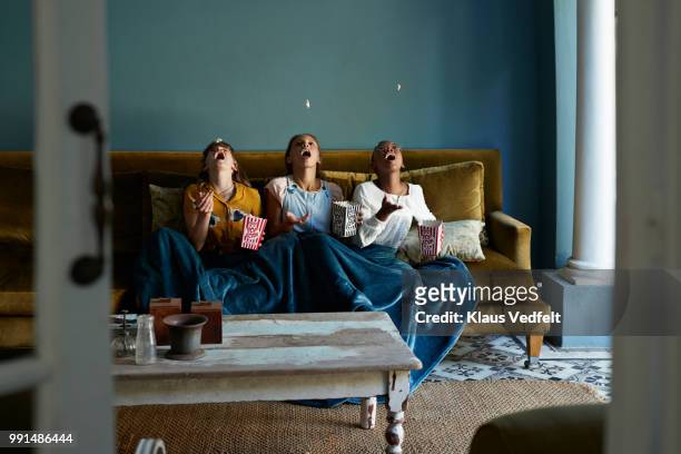 3 friends catching popcorn with the mouth - sofa stock-fotos und bilder