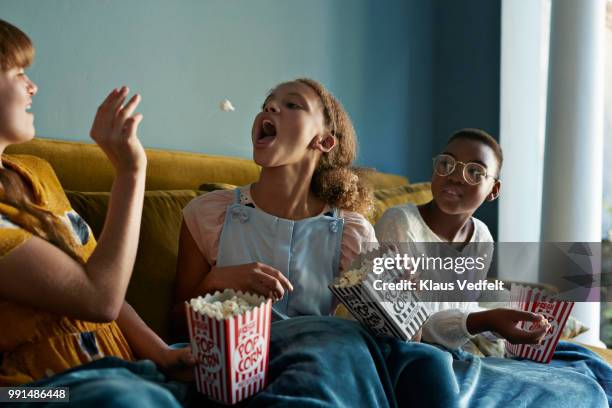 friends throwing popcorn and catching with mouth, at home - flip over stockfoto's en -beelden