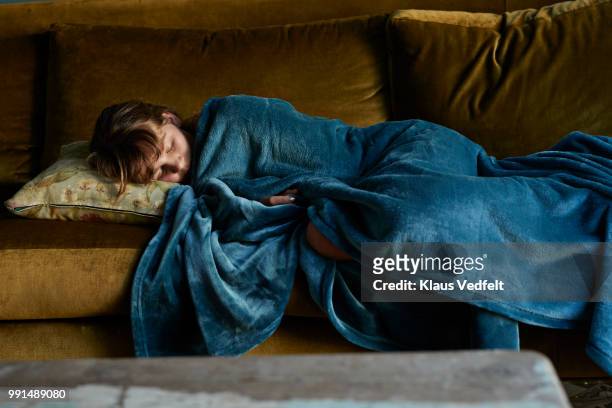 Girl sleeping on couch, wrapped in blue blanket