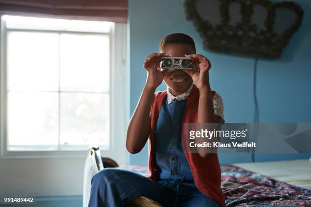Girl looking in camera with retro binoculars