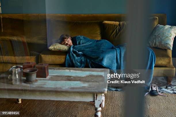 girl sleeping on couch, wrapped in blue blanket - klaus vedfelt stock-fotos und bilder