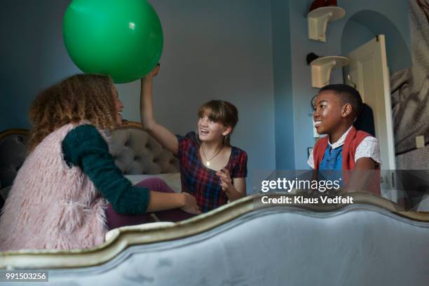 tween girlfriends playing with giant balloon, at home - klaus vedfelt stock-fotos und bilder