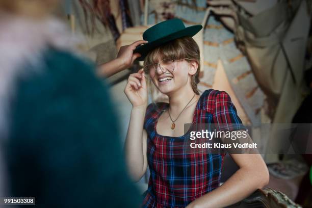 girl sitting on bed and trying hat and glasses with friends - klaus vedfelt fotografías e imágenes de stock