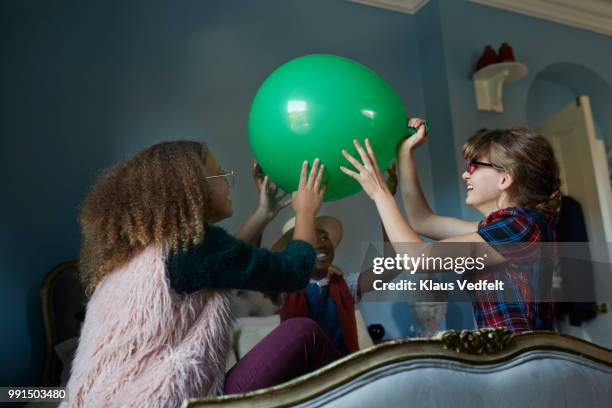 tween girlfriends playing with giant balloon, at home - wonky fringe stock pictures, royalty-free photos & images