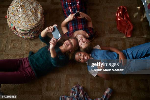 top view of 3 tween girls laughing and looking at their smartphones - klaus vedfelt fotografías e imágenes de stock