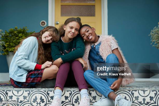 Portrait of 3 happy girlfriends, relaxing on porch