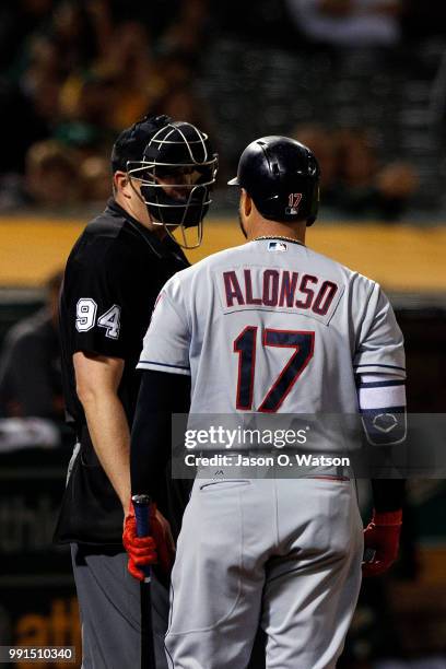 Yonder Alonso of the Cleveland Indians argues a called strike with umpire Lance Barrett during the ninth inning against the Oakland Athletics at the...