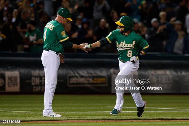 Jed Lowrie of the Oakland Athletics is congratulated by third base coach Matt Williams after hitting a home run against the Cleveland Indians during...