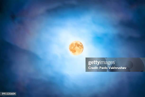 night view at the full moon through moving blue clouds - blue moon stock pictures, royalty-free photos & images