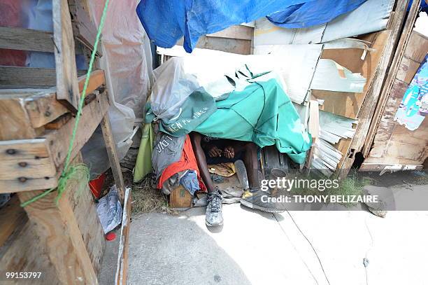 Haitian man , victim of the January 12 earthquake, finds refuge under a tarp at a tent city on May 12, 2010 in Port-au-Prince. Protesters are...