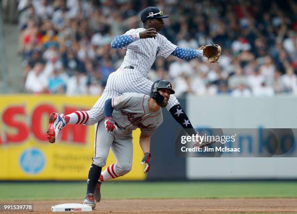 Didi Gregorius of the New York Yankees leaps over Ender Inciarte of the Atlanta Braves after a force out at second base during the first inning at...