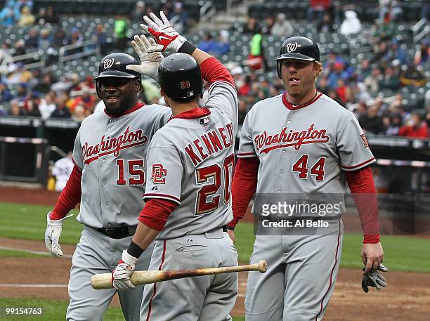 Cristian Guzman, Adam Kennedy, and Adam Dunn of the Washington Nationals celebrate scoring two runs against The New York Mets during their game on...