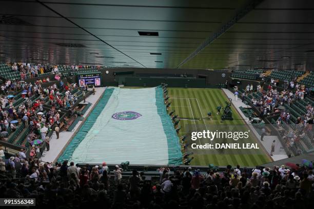 The covers are brought on as rain stops play between Croatia's Marin Cilic and Argentina's Guido Pella in their men's singles second round match on...