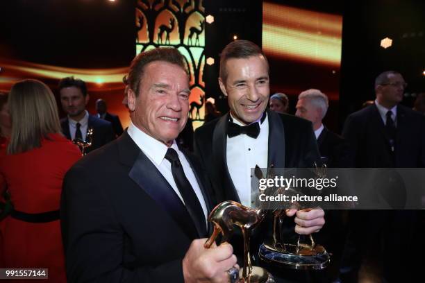 Actor Arnold Schwarzenegger and moderator Kai Pflaume standing onstage holding their prizes after the awards ceremony of the 69th edition of the...