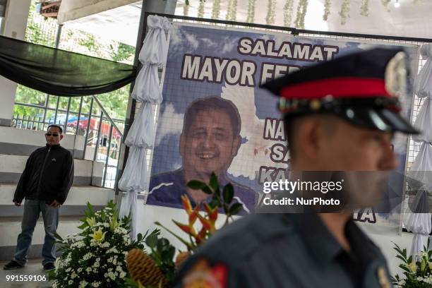 Police honour guard and a private bodyguard stands next to a tarpaulin of General Tinio Mayor Ferdinand Bote, who was assassinated by unidentified...