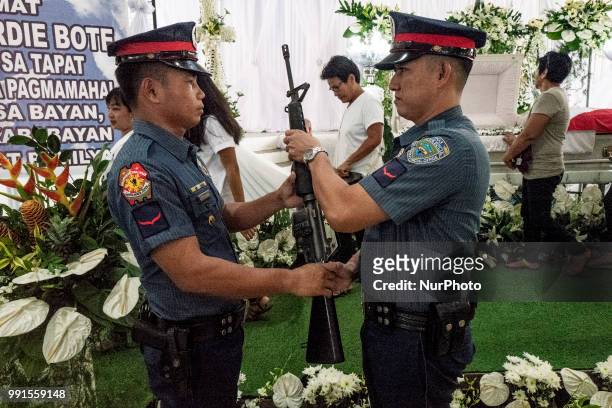 Police honour guards stand next to the remains of General Tinio Mayor Ferdinand Bote, who was assassinated by unidentified gunmen on motorcycles,...