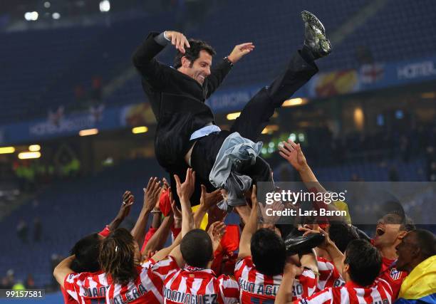 Atletico Madrid players throw their head coach Quique Sanchez Flores in the air celebrating their victory after the UEFA Europa League trophy after...