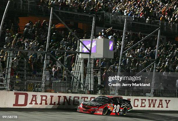 Denny Hamlin, driver of the Z-Line Designs / Operations Helmet Toyota, heads across the start/finish line to take the checkered flag and win the...