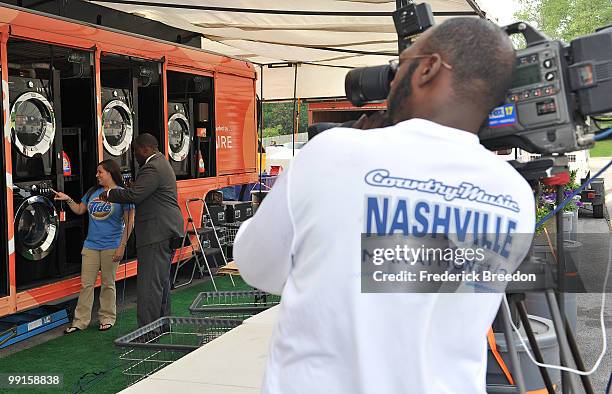 Member of the Tide's Loads Of Hope mobile laundry crew is interviewed by a news caster at Loads of Hope Truck - Laundry Drop-Off Site: Dollar General...