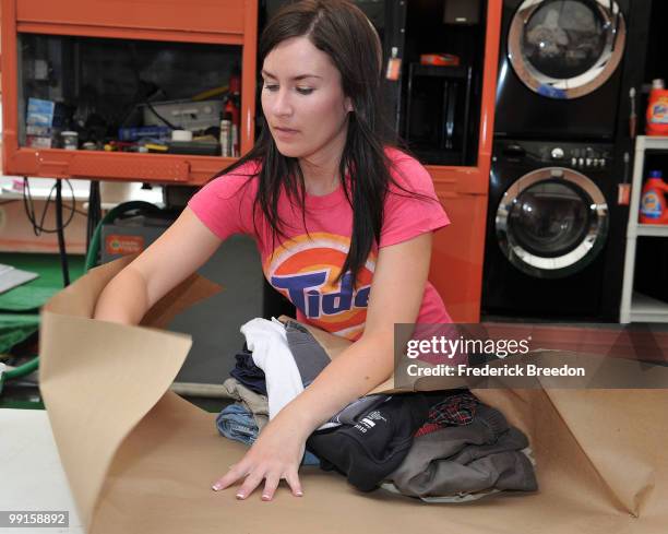 Member of the Tide's Loads Of Hope mobile laundry crew folds clean clothes at Tide's Loads of Hope Truck - Laundry Drop-Off Site: Dollar General on...