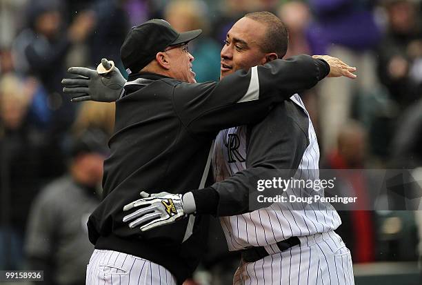 Catcher Miguel Olivo of the Colorado Rockies is congratulated by coach Tom Runnels after his game winning solo homerun off of Chad Durbin of the...