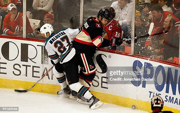 Brent Seabrook of the Chicago Blackhawks hits the boards with Manny Malhotra of the San Jose Sharks at the United Center on December 22, 2009 in...