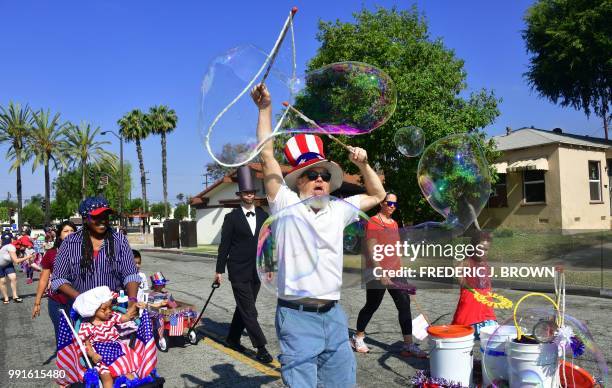 Participant dresses as former US president Abraham Lincoln as people follow the bubble maker during a parade in San Gabriel, California on July 4,...