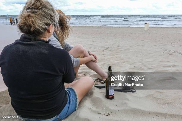 Two woman drinking a wine on a beach are seen in Sopot, Poland on 30 June 2018 First weekend of summer break met tourists with very windy weather....