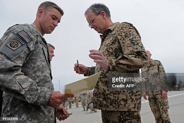 Chief of staff at NATO's International Security Assistance Force , German Lieutenant General Bruno Kasdorf awards a medal to a US army soldier during...