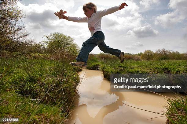 young girl leaping over stream - paul mansfield photography stock pictures, royalty-free photos & images