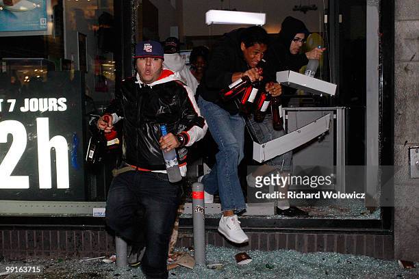 Looters run out of the broken window of a liquor store with bottles of alcohol in downtown Montreal after the Montreal Canadiens defeated the...