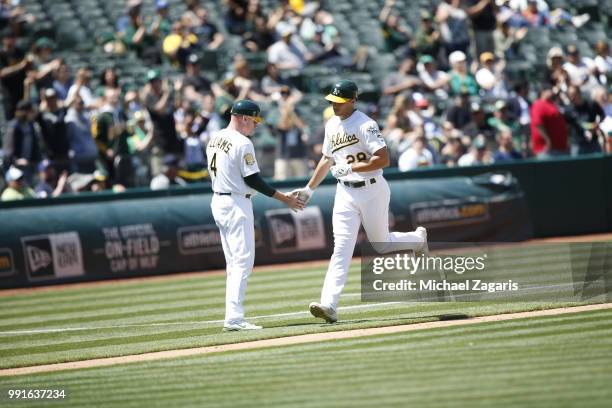 Matt Olson of the Oakland Athletics is congratulated by Third Base Coach Matt Williams while running the bases after hitting a home run during the...