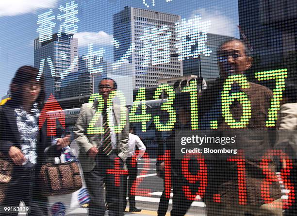 Pedestrians are reflected in an electronic stock board showing the Hang Seng Index outside a securities firm in Tokyo, Japan, on Thursday, May 13,...