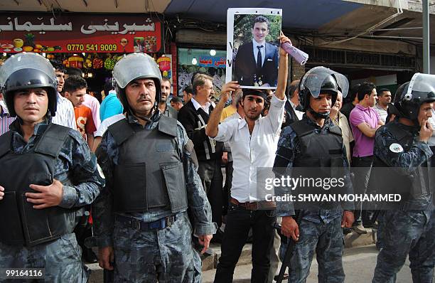 Iraqi policemen stand guard as a demonstrator holds a picture of killed Kurdish journalist and student Sardasht Osman during a protest against his...