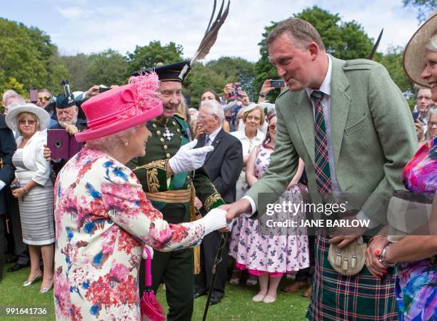 Britain's Queen Elizabeth II meets former Scotland ruby union player Doddie Weir as she hosts the annual garden party at the Palace of Holyroodhouse...
