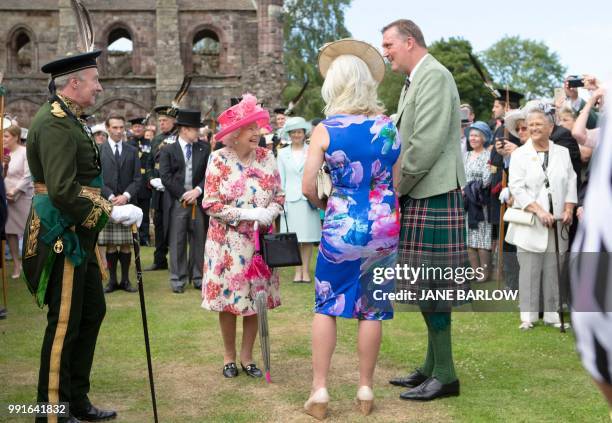 Britain's Queen Elizabeth II meets former Scotland ruby union player Doddie Weir and his wife Kathy as she hosts the annual garden party at the...