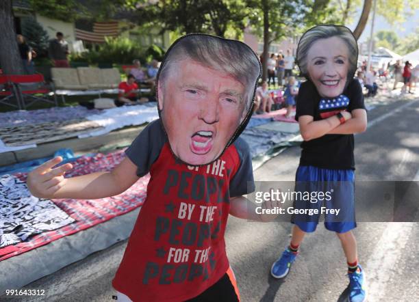 Two kids with Donald Trump and Hillary Clinton masks walks Center Street during the Provo Freedom Festival Parade on July 4, 2018 in Provo, Utah....