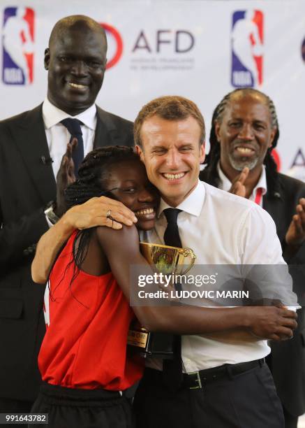 French President Emmanuel Macron gives a trophee to a young basketball player in the French Louis Pasteur high school on July 4 in Lagos.